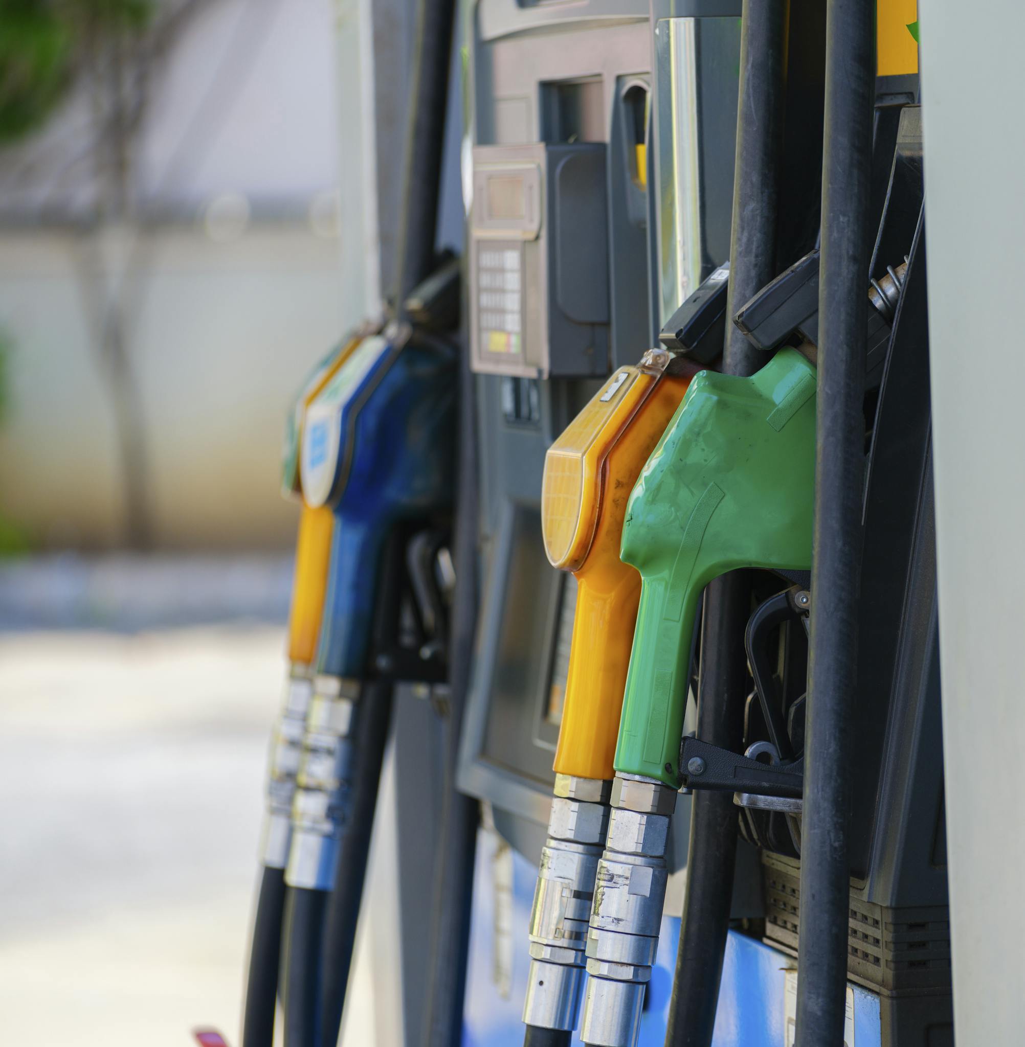 Close-up of vibrant fuel nozzles at a gasoline station showcasing diesel, gas, and petrol options.